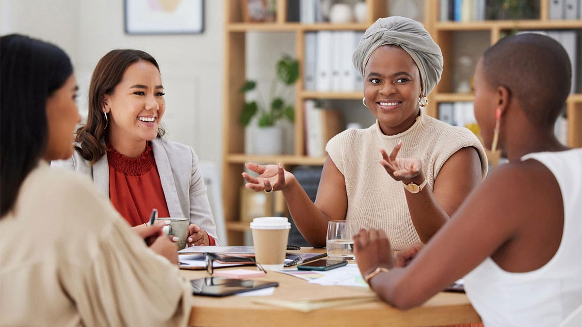 Grupo de empreendedoras conversando e trocando ideias em reunião, simbolizando redes de apoio para empreendedores e fortalecimento coletivo nos negócios.